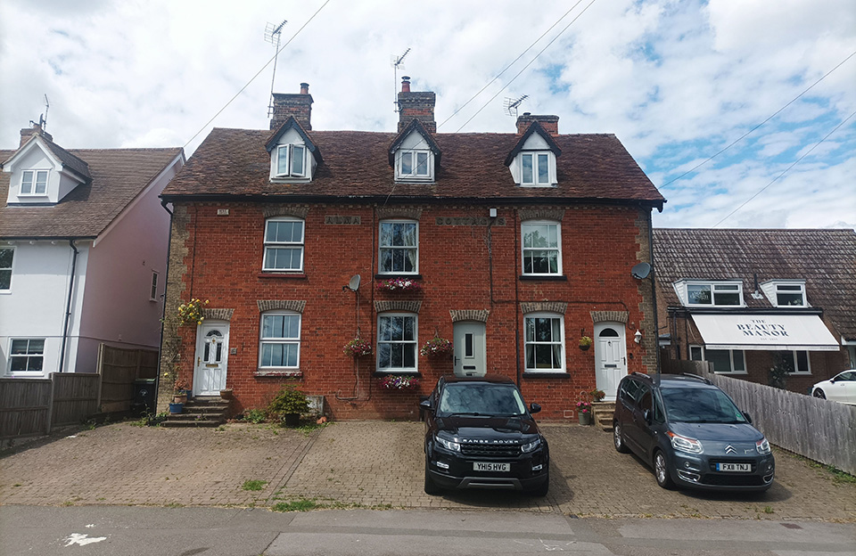 Dormer windows and central stack chimneys create strong character for red brick terraces.