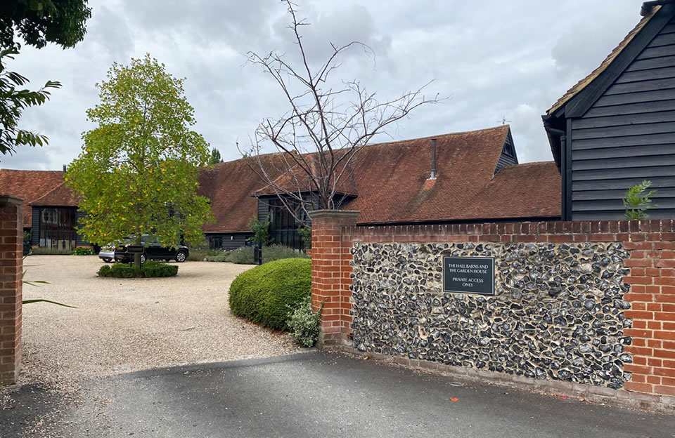 Black weatherboarded barn conversion with dormers, shared courtyard and stone wall boundary at Hall Barn and Garden House.