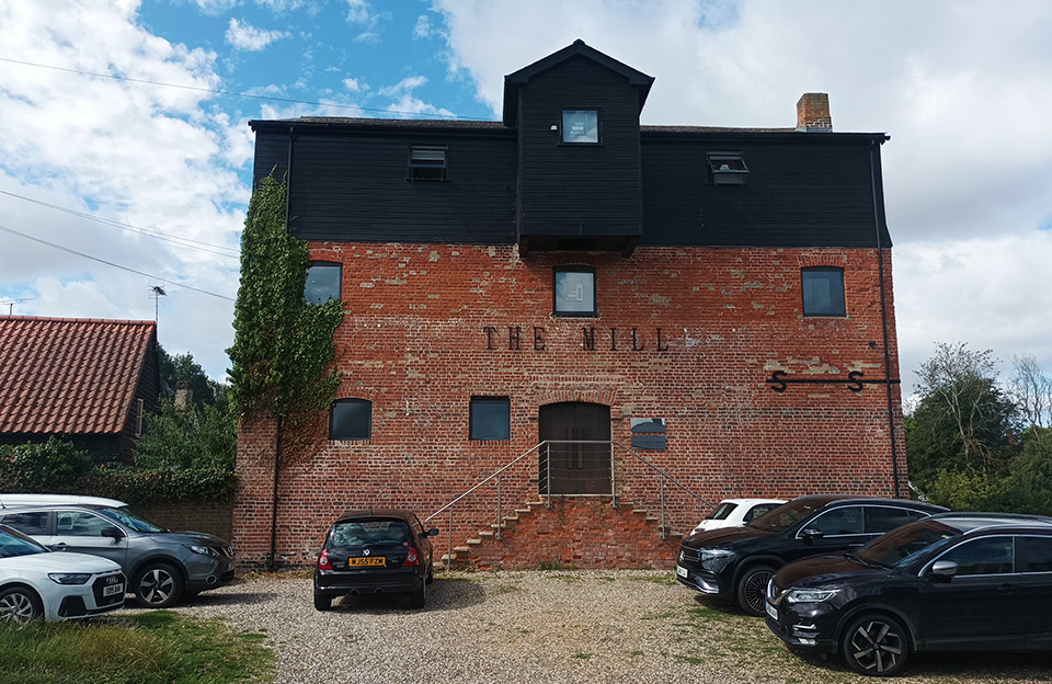 Red brick mill conversion into non-residential uses while retaining historic facade details in Hatfield Heath.