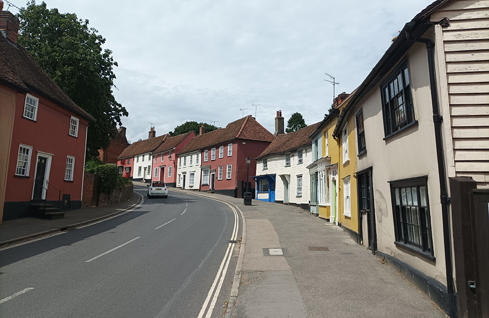 Curved High Street in Thaxted with coloured render moving uphill creates sense of anticipation.