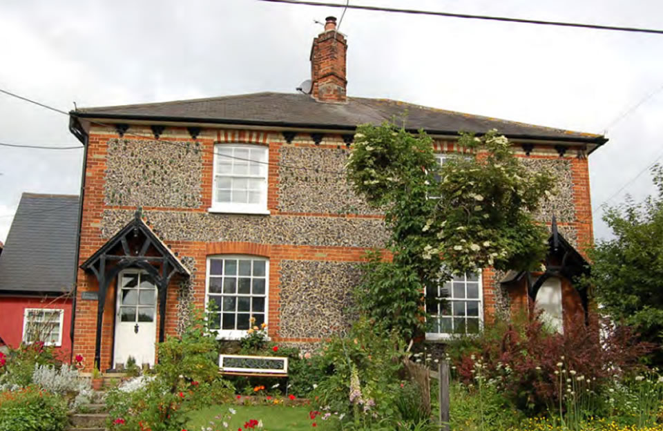 Flint Cottages with red brick quoins on the High Street at Widdington.