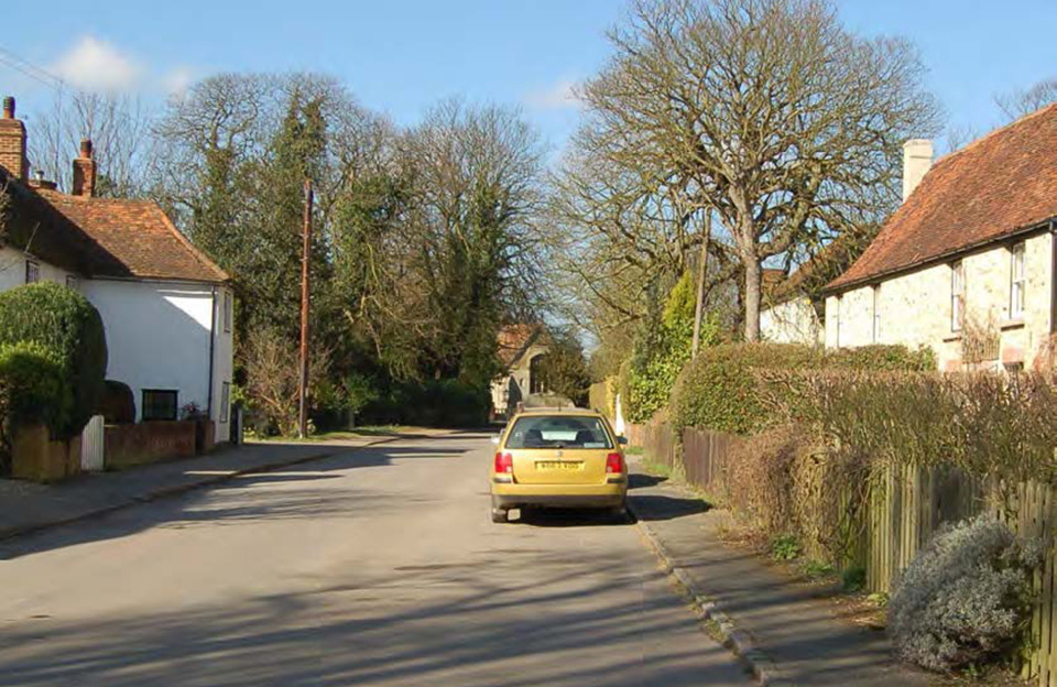 Mature trees animating grass verges and creating enclosure along the High Street, Debden.