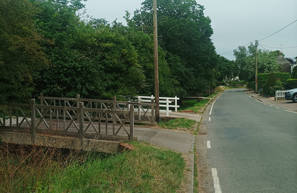 Bridges to homes over swales and green verges on the Main Street, Arkesden.