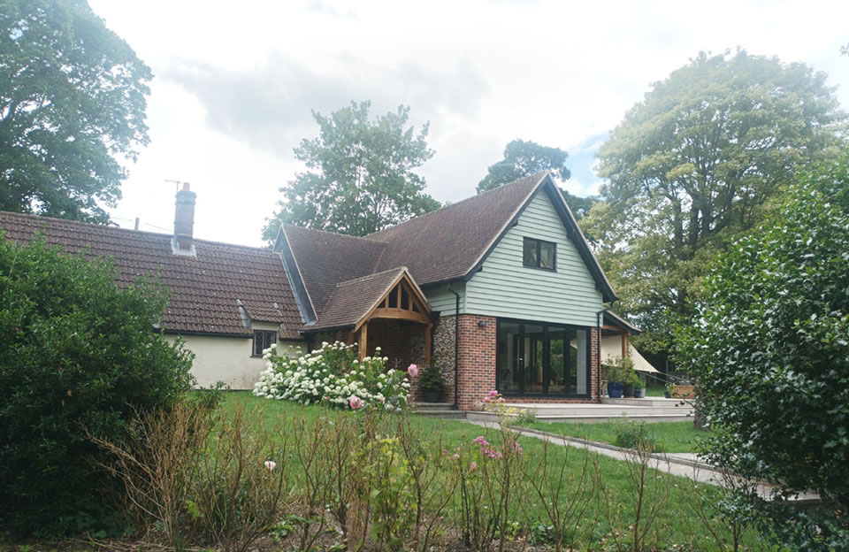 Modern example of house extension in Little Bardfield using local materials such as flint and white weatherboarding.